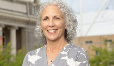 A professor smiles while standing outside on the Syracuse University campus.