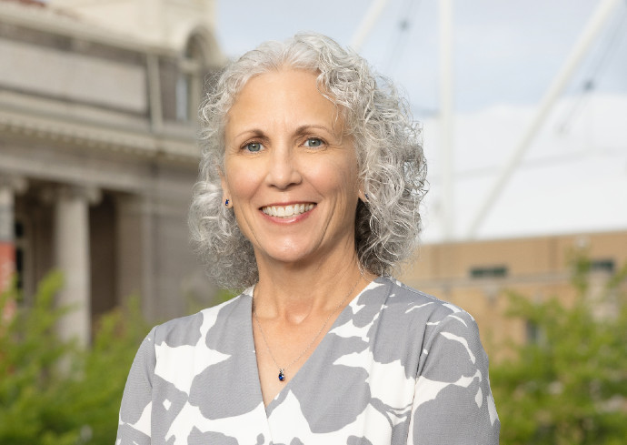 A professor smiles while standing outside on the Syracuse University campus.