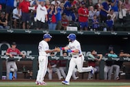 Texas Rangers first baseman Jake Burger celebrates with third base coach Tony Beasley (27)...