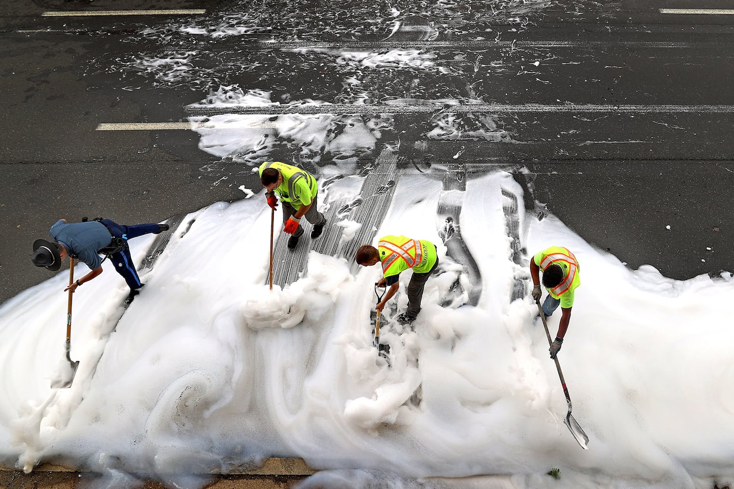 A Massachusetts state trooper and MassDOT employees moved foam off the highway after a car fire was extinguished on July 11. An electric vehicle caught fire just after 7 a.m. on the Massachusetts Turnpike extension westbound in Boston, causing traffic to back up through the city.