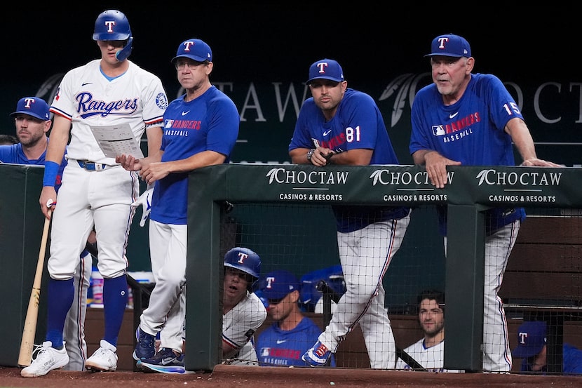 Texas Rangers outfielder Josh Jung talks with hitting coach Brett Boone alongside bench...