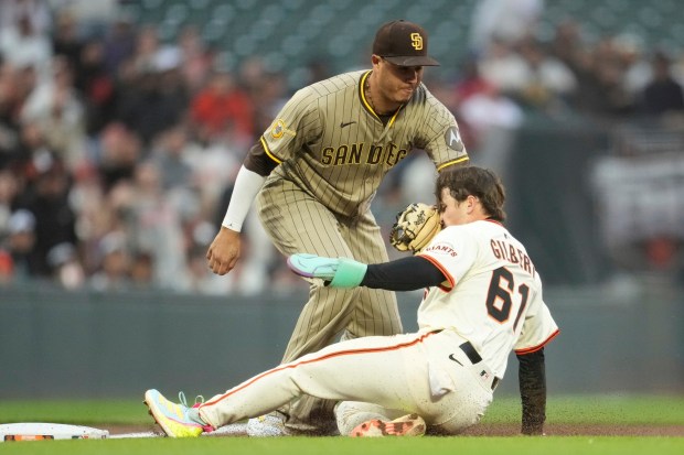 San Francisco Giants' Drew Gilbert (61) is tagged out by San Diego Padres third baseman Manny Machado while trying to reach third base after stealing second base during the third inning of a baseball game in San Francisco, Monday, Aug. 11, 2025. (AP Photo/Jeff Chiu)