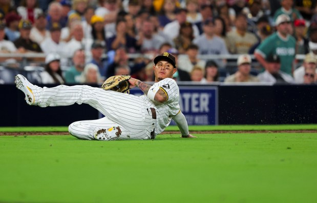 Manny Machado #13 of the San Diego Padres falls while attempting to throw out a Boston Red Sox runner at first base during the ninth inning at Petco Park on Saturday, Aug. 9, 2025 in San Diego, CA. (Meg McLaughlin / The San Diego Union-Tribune)
