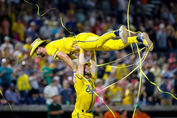 Kyle Luigs (12) is hoisted into the air by teammate Bill Leroy (1) after the Savannah Bananas defeated the Party Animals at Harbor Park in Norfolk, Virginia, on Aug. 15, 2024. (Billy Schuerman / The Virginian-Pilot)