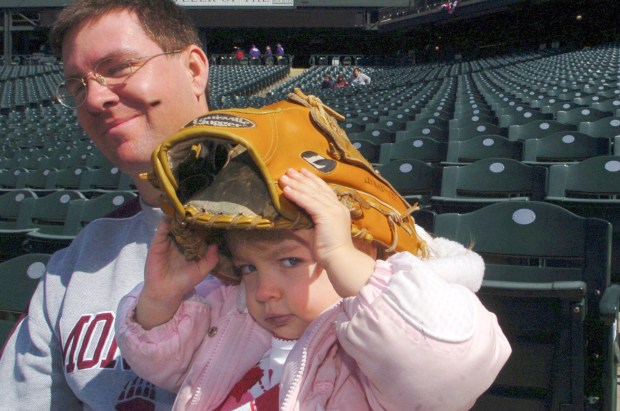 DENVER, COLORADO -- April 2, 2006-- The Colorado Rockies baseball team held an open practice at Coors Field Sunday in preparation for the season opener Monday in Denver. 2-year-old Emily Sauvageau covers he head wih a glove as dad, Dan Sauvageau watches the team. <cq>  (Denver Post Staff Photo by Brian Brainerd)