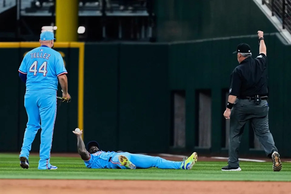 Rangers right fielder Adolis Garcia holds up the ball for the umpire Manny Gonzalez, right, after making a sliding catch on a fly out by Philadelphia Phillies’ Nick Castellanos as Rowdy Tellez (44) looks on in the second inning AP