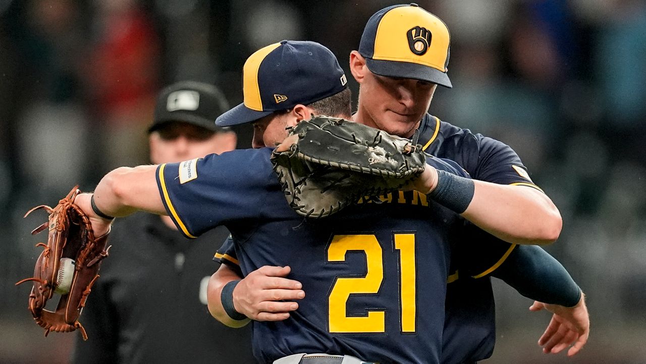 Milwaukee Brewers' Caleb Durbin (21) embraces Andrew Vaughn (28) after a baseball game against the Atlanta Braves, Tuesday, Aug. 5, 2025, in Atlanta.