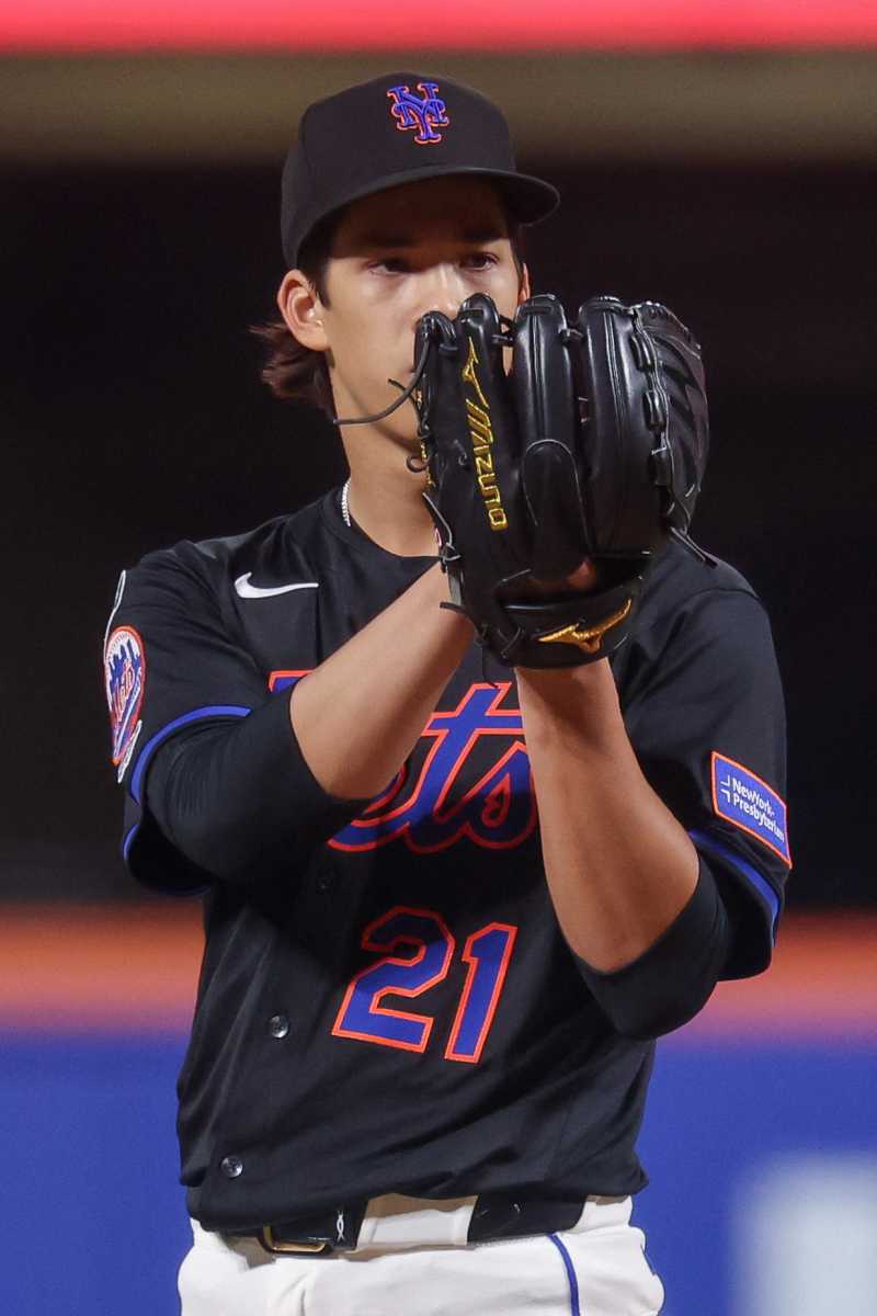 Jonah Tong staring into his glove about to throw ball for Mets