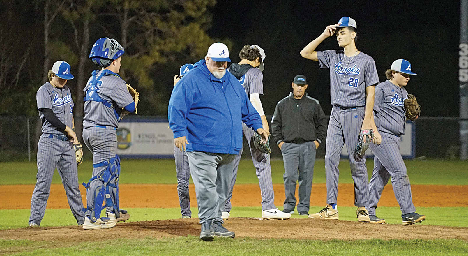 Apopka baseball's former head coach, Bobby Brewer, walks off the mound after speaking with pitcher Tyler Spaid.