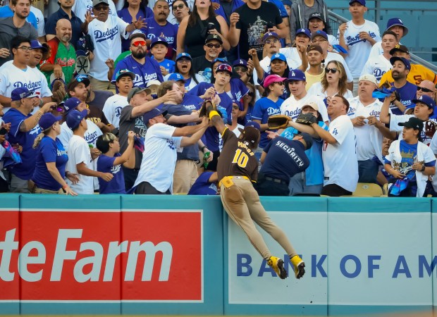 San Diego Padres Jurickson Profar leaps into the stands to steal a home run from Dodgers' Mookie Betts in the first inning during Game 2 of the NLDS at Dodger Stadium on Sunday, Oct. 6, 2024.  (K.C. Alfred / The San Diego Union-Tribune)