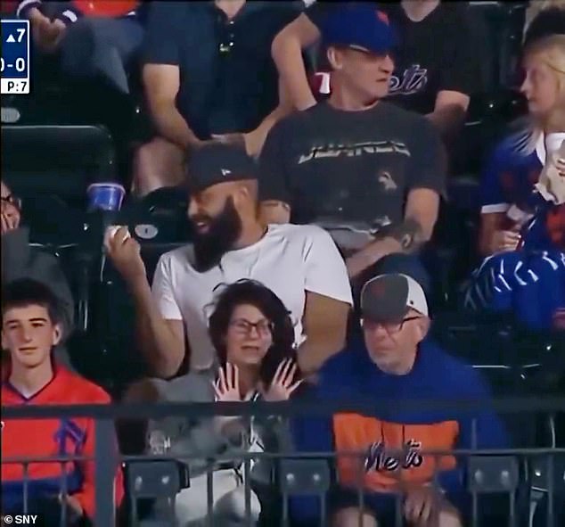 The fan in white smugly shows his prize as the older fan and his companion try to ignore him
