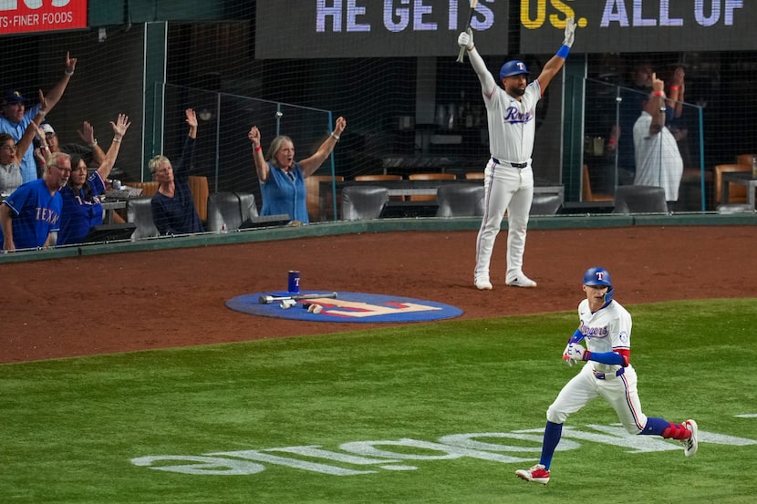 Texas Rangers' Michael Helman runs as teammate Ezequiel Duran, top, and spectators react to...