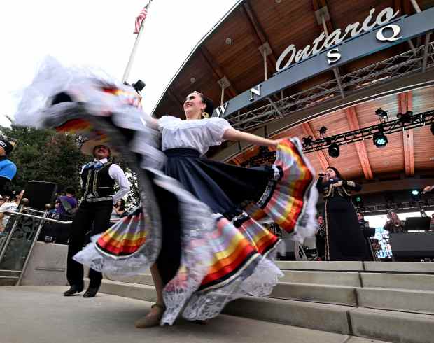 A ballet folklorico group performs for Dodger fans as they...