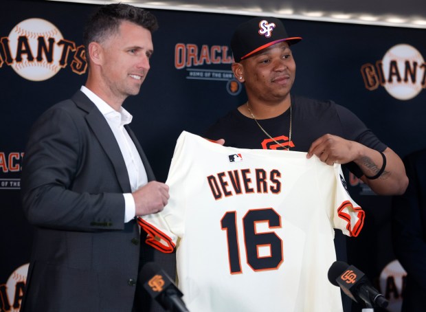 San Francisco Giants President of Baseball Operations Buster Posey, left, and San Francisco Giants' Rafael Devers (16) hold his jersey up as Devers is introduced before their game against the Cleveland Guardians at Oracle Park in San Francisco, Calif., on Tuesday, June 17, 2025. (Nhat V. Meyer/Bay Area News Group)