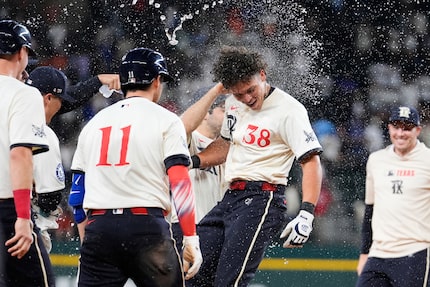 Texas Rangers' Kyle Higashioka (11) and Dustin Harris, (38) celebrate with the team after...