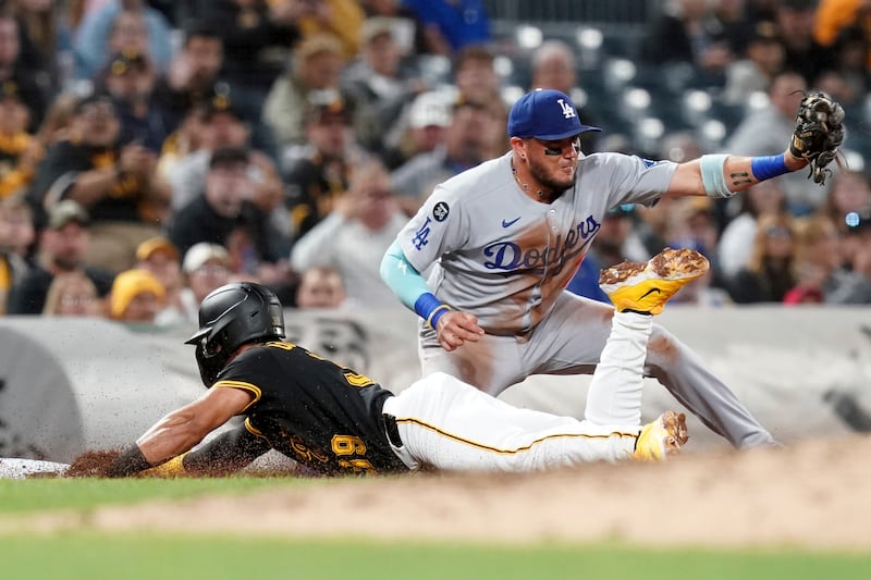 Photo of a baseball player diving for a stop, and another trying to catch the ball.
