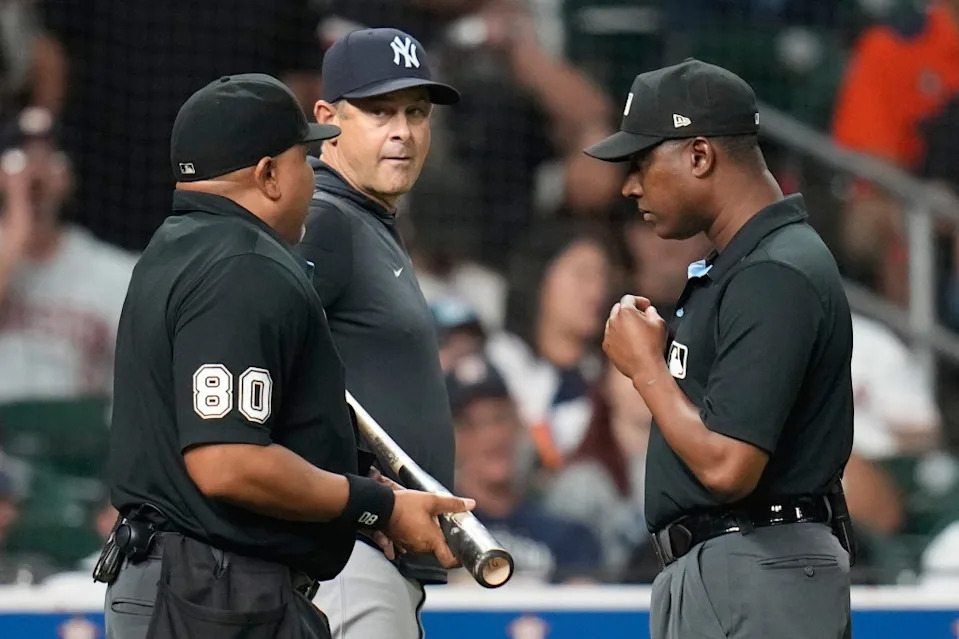 Home plate umpire Adrian Johnson, left, holds Houston Astros’ Taylor Trammell’s bat as he, New York Yankees manager Aaron Boone, center, and Ramon De Jesus, right, discussed the scuff on it during the ninth inning on Thursday, Sept. 4, 2025, in Houston. AP