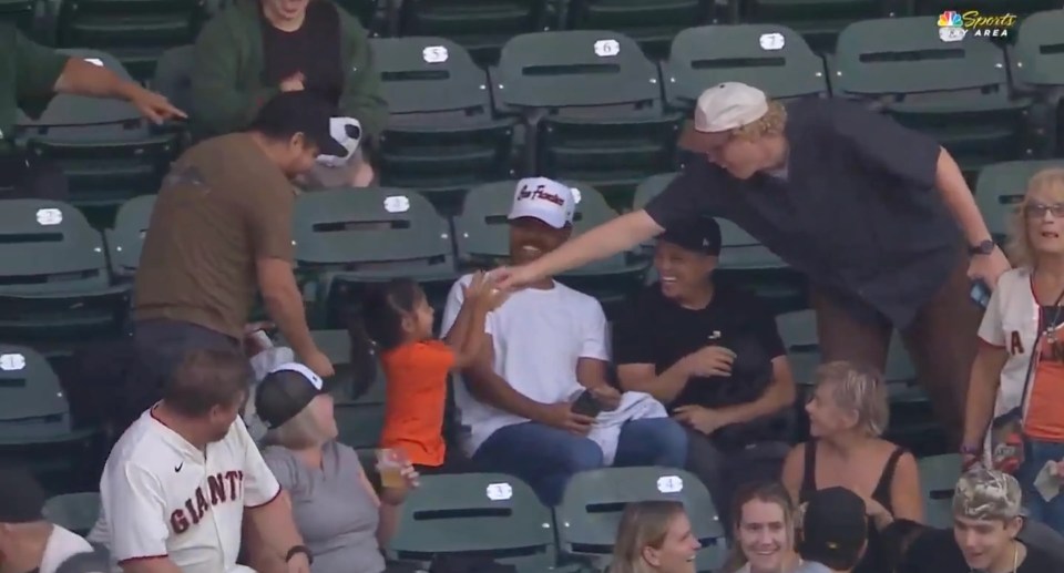 Screenshot of a young girl high-fiving a man in a baseball stadium.