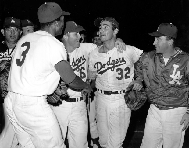 Dodgers pitcher Sandy Koufax (32) is congratulated by teammates Ron...