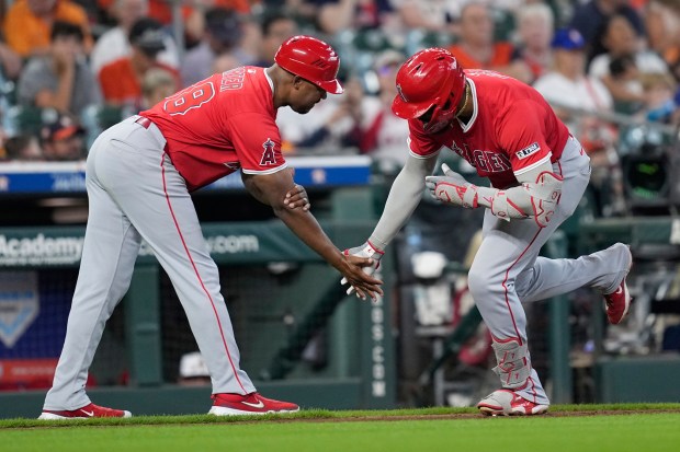 The Angels’ Jo Adell, right, celebrates with third base coach...