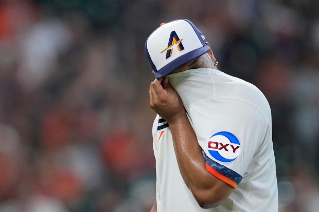 Houston Astros starting pitcher Luis Garcia wipes his face as...