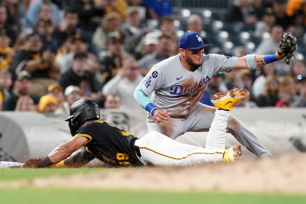The Pittsburgh Pirates’ Nick Gonzales, bottom, slides safely into third...