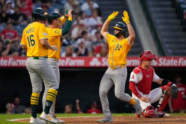 Athletics’ Colby Thomas, second from right is congratulated by Nick...