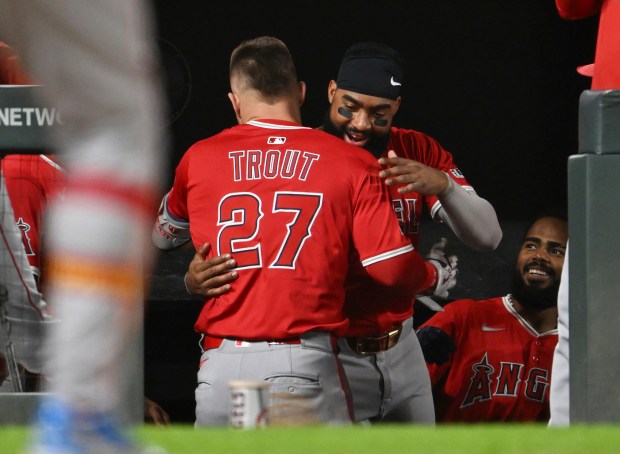 Angels designated hitter Mike Trout, left, is hugged by teammate...