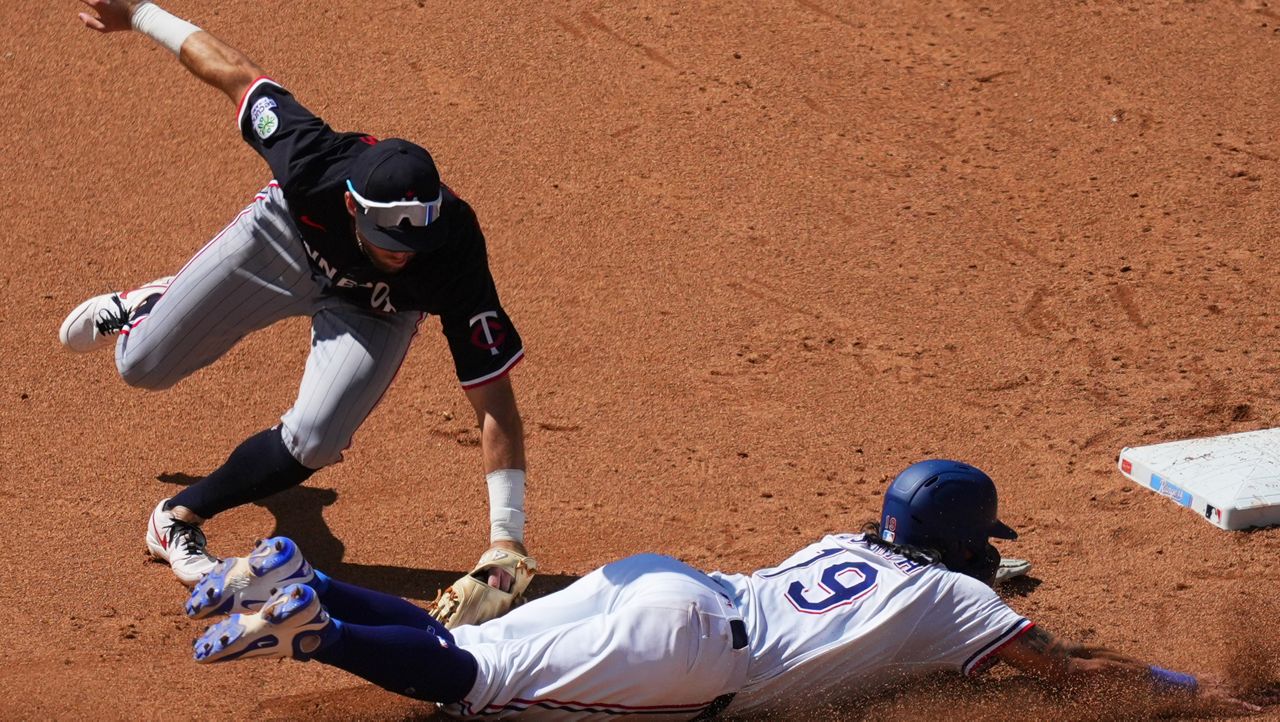 Minnesota Twins second baseman Kody Clemens, top, tags out Texas Rangers' Alejandro Osuna trying to steal the bag during the fifth inning of a baseball game Thursday, Sept. 25, 2025, in Arlington. (AP Photo/Julio Cortez)