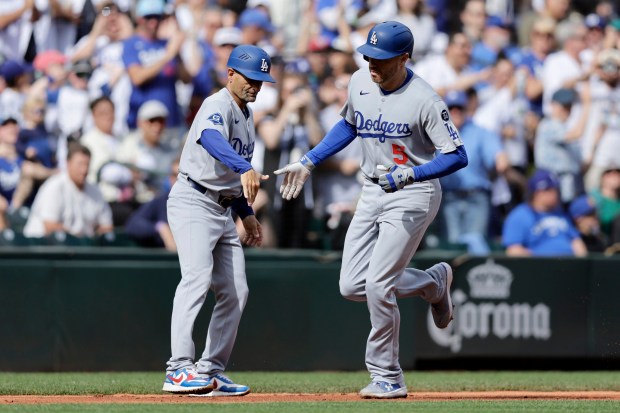 Dodgers’ Freddie Freeman, right, is greeted by third base coach...