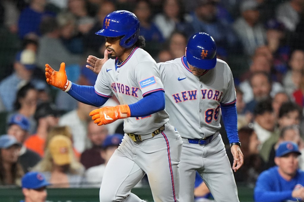 New York Mets' Francisco Lindor, left, is congratulated by third base coach Mike Sarbaugh after hitting a solo home run during the third inning of a baseball game against the Chicago Cubs in Chicago, Thursday, Sept. 25, 2025. 