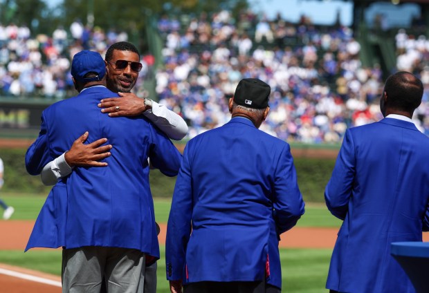 Chicago Cubs Hall of Famer Derrek Lee hugs fellow Cubs Hall of Famers before throwing out the first pitch at Wrigley Field on Sept. 7, 2025, in Chicago. (Stacey Wescott/Chicago Tribune)