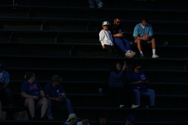 A young fan squints from the setting sun in the left-field bleachers before a Cubs-Mets game at Wrigley Field on Sept. 25, 2025, in Chicago. (John J. Kim/Chicago Tribune)