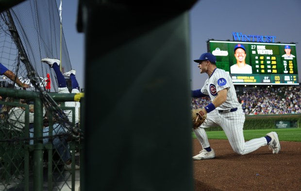 Cubs shortstop Dansby Swanson, left, falls into the security netting after catching a pop up from Mets designated hitter Mark Vientos in the first inning at Wrigley Field on Sept. 25, 2025, in Chicago. (John J. Kim/Chicago Tribune)