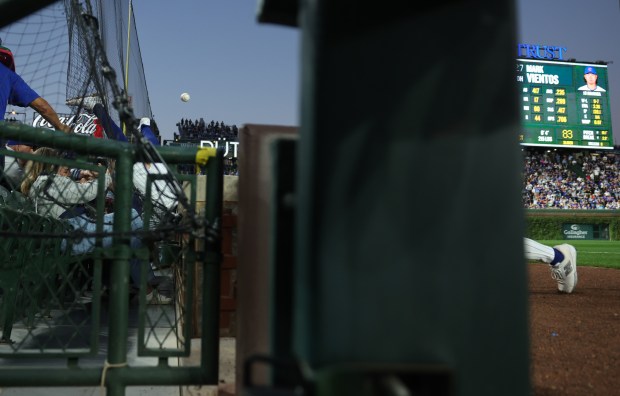 Cubs shortstop Dansby Swanson, left, tosses the ball to third baseman Matt Shaw, right, after falling into the security netting while catching a pop up from Mets designated hitter Mark Vientos in the first inning at Wrigley Field on Sept. 25, 2025, in Chicago. (John J. Kim/Chicago Tribune)
