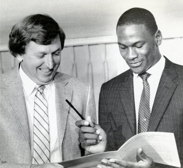 Michael Jordan, right, looks over the multi-million dollar contract he signed with the Chicago Bulls as Bulls general manager Rod Thorn looks on Sept. 12, 1984. (Ray Foli/UPI photo)