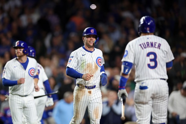 Chicago Cubs second base Nico Hoerner (2) smiles at Chicago Cubs first base Justin Turner (3) after scoring off a two RBI double from Chicago Cubs first base Carlos Santana (41) during the first inning at Wrigley Field Tuesday Sept. 23, 2025, in Chicago. (Armando L. Sanchez/Chicago Tribune)