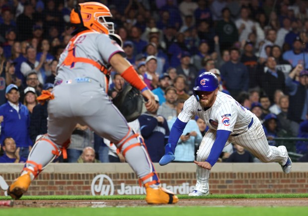 Chicago Cubs first baseman Michael Busch begins his slide before being tagged out at home plate by New York Mets catcher Francisco Alvarez in the first inning of a game at Wrigley Field in Chicago on Sept. 24, 2025. (Chris Sweda/Chicago Tribune)