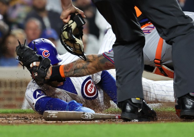 Chicago Cubs first baseman Michael Busch is tagged out at home plate by New York Mets catcher Francisco Alvarez in the first inning of a game at Wrigley Field in Chicago on Sept. 24, 2025. (Chris Sweda/Chicago Tribune)