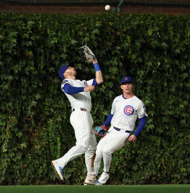 Chicago Cubs left fielder Ian Happ (left) catches a long fly ball for an out in the fourth inning of a game against the New York Mets at Wrigley Field in Chicago on Sept. 24, 2025. (Chris Sweda/Chicago Tribune)