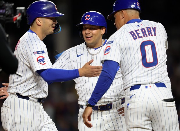 Chicago Cubs right fielder Seiya Suzuki (left), designated hitter Moisés Ballesteros (center), and third base coach Quintin Berry (0), celebrate after Suzuki drove in a run on a double in the third inning of a game against the New York Mets at Wrigley Field in Chicago on Sept. 24, 2025. (Chris Sweda/Chicago Tribune)
