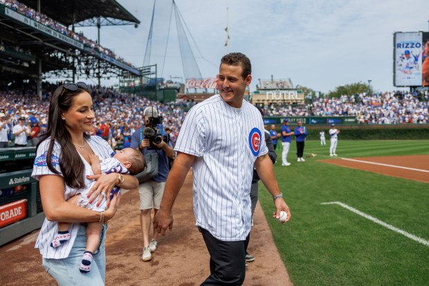 Former Cubs first baseman Anthony Rizzo and his wife Emily walk on the field to throw out the first pitch before the Cubs play the Tampa Bay Rays at Wrigley Field after the Cubs announced he would retire and become an ambassador for the team he helped lead to a World Series in 2016 Saturday Sept. 13, 2025, in Chicago. (Armando L. Sanchez/Chicago Tribune)