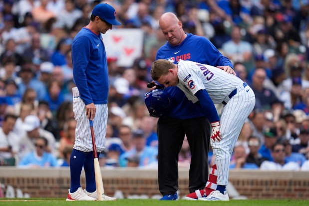 Cubs manager Craig Counsell, left, and a team trainer check on center fielder Pete Crow-Armstrong during an at-bat in the sixth inning against the Nationals on Saturday, Sept. 6, 2025, at Wrigley Field. Crow-Armstrong fouled a ball off his right knee and later left the game. (Erin Hooley/AP)