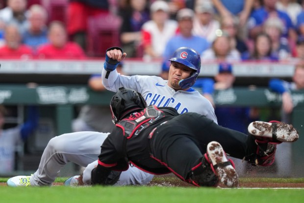 Chicago Cubs' Seiya Suzuki, right, is tagged out at home plate by Cincinnati Reds catcher Jose Trevino during the first inning of a baseball game, Friday, Sept. 19, 2025, in Cincinnati. (AP Photo/Jeff Dean)