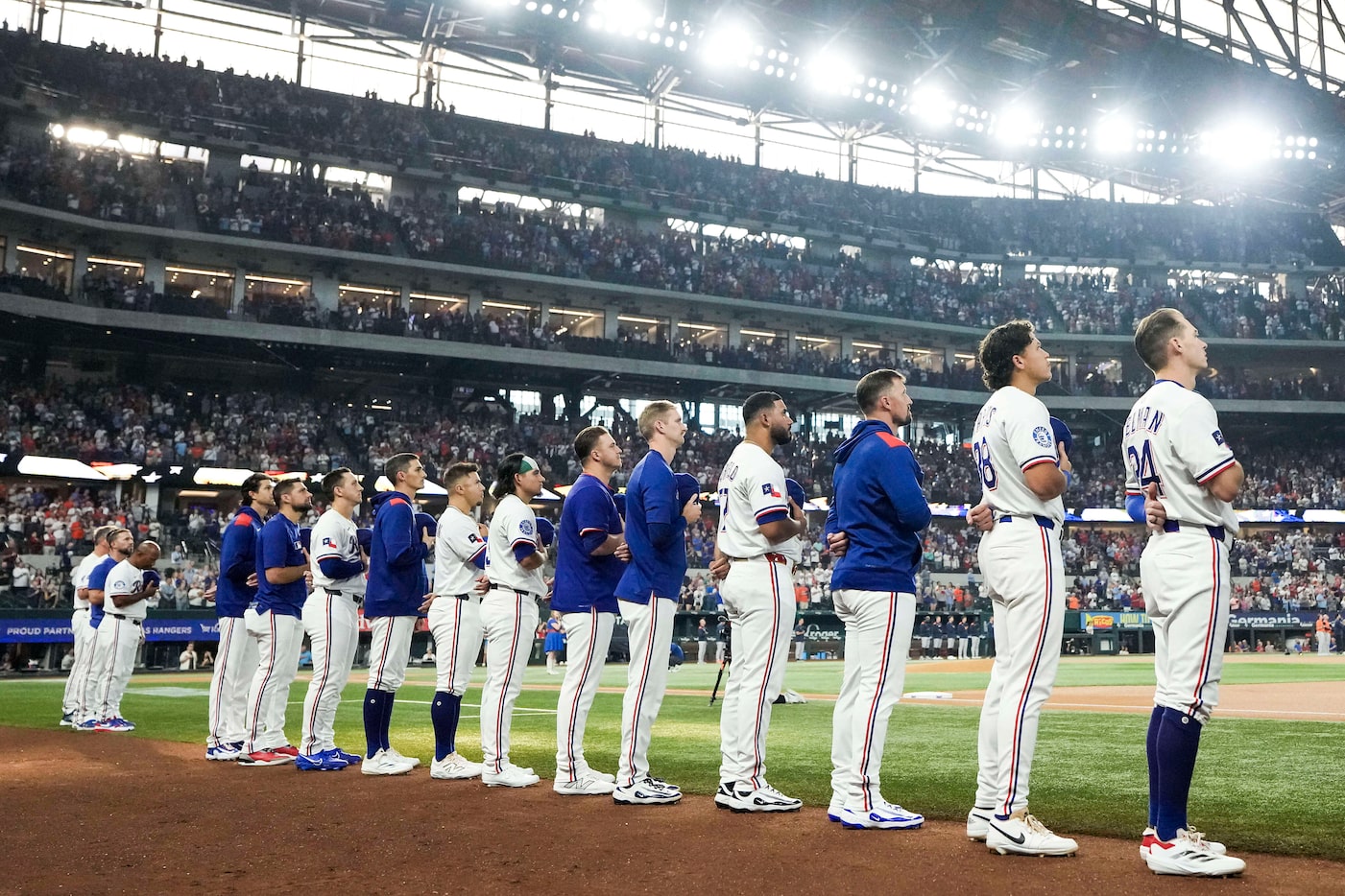Texas Rangers players stand for the the national anthem before a baseball game against the...