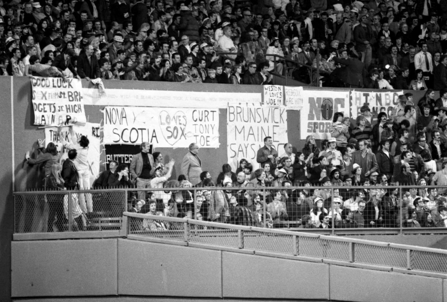 Red Sox fans put up signs along the center-field wall at Fenway Park during Game 7.