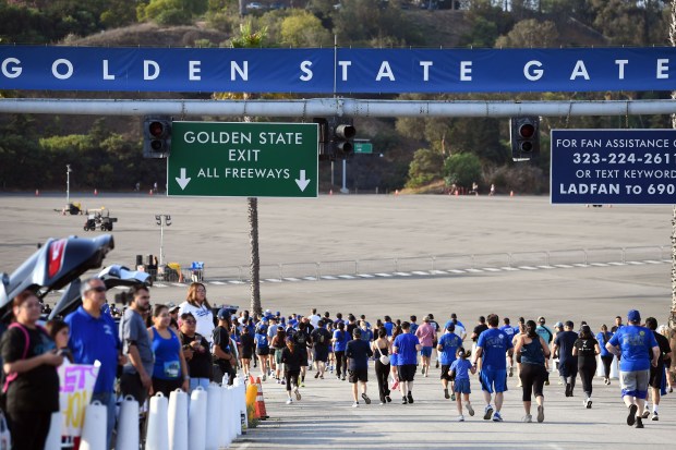 Runners make their way around an empty Dodger Stadium parking...