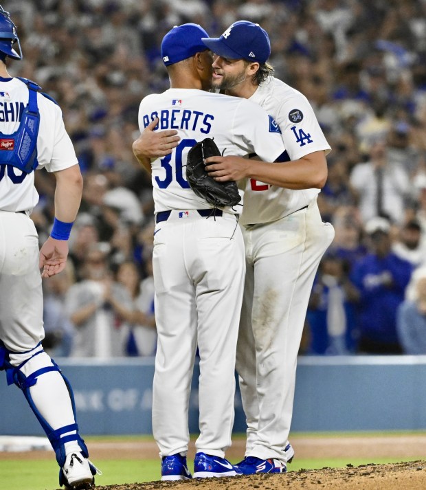 Dodgers starting pitcher Clayton Kershaw, right, hugs Manager Dave Roberts...