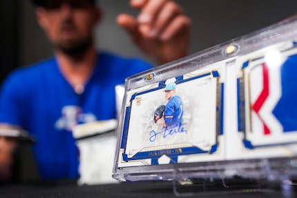 Texas Rangers pitcher Shawn Armstrong reaches for a card featuring teammate Jack Leiter from...