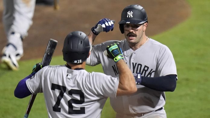 Dodgers -New York Yankees' Austin Wells (28) celebrates with José Caballero (72) after Wells hit a home run off Tampa Bay Rays pitcher Pete Fairbanks during the 10th inning of a baseball game Wednesday, Aug. 20, 2025, in Tampa, Fla. (AP Photo/Chris O'Meara)